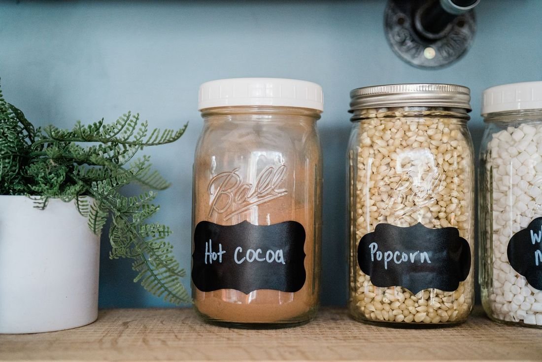 Beberapa jar kaca berlabel tersusun di rak dapur